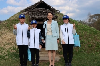 (写真3)世界遺産に認定された御所野遺跡の前で記念写真に写る中谷大使と愛護少年団団長・副団長(小学生)