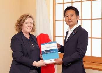 正面を向き、ハース前議長から2021年3月に公表した報告書の手交を受ける、上杉政務官の様子