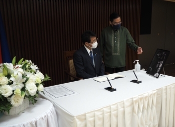 記帳を前に説明を聞く三宅政務官の様子