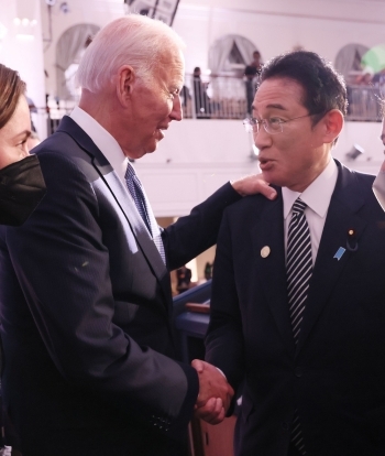 岸田総理の肩に左手を添え、右手で握手を交わすバイデン大統領と、握手で応じる岸田総理の様子