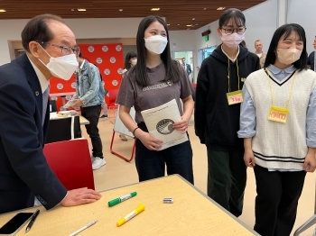 ホワイトボードに書いたアイディアを、笑顔で説明する日本の学生達と、笑顔でその説明を聞く、朝長佐世保市長の様子