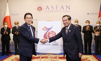 日カンボジア外交関係樹立70周年ロゴマークを前に、フン・セン首相と握手する岸田総理大臣