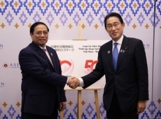 ロゴマークを背景に、握手をする岸田総理大臣とチン首相