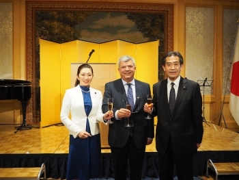 正面を向き、シャンパングラスを持ち、記念撮影に応じる、吉川政務官、ドランガ大使らの様子
