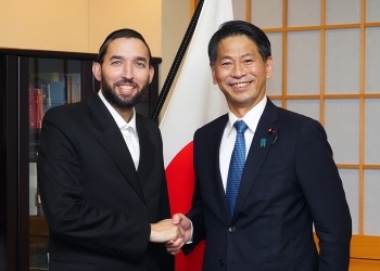 正面を向き、笑顔で握手を交わす、山田副大臣とアイケンスタイン議員の様子