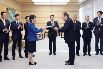 供与する発電機の目録をコルスンスキー大使に贈呈する上川議員、および拍手する岸田総理らの様子