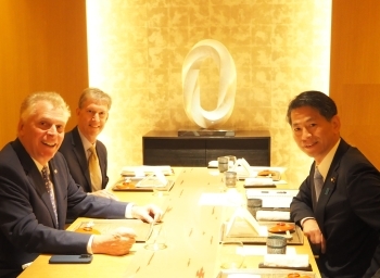 テーブルにつき、写真撮影に応じる、山田副大臣とマコーリフ元州知事らの様子