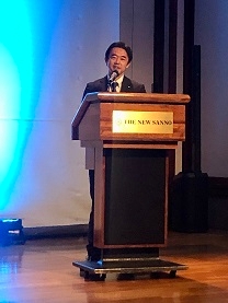 演台に立ち、挨拶を行う、穂坂政務官の様子