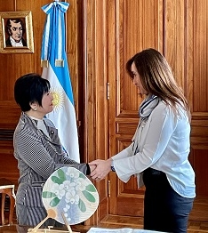 向かい合い、両手で握手を交わす、山東特派大使とビジャルエル副大統領の様子
