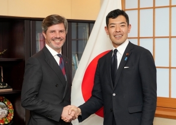 正面を向き、笑顔で握手を交わす、辻󠄀副大臣とエヴラー大使の様子