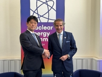 グロッシー事務局長と握手しながら記念撮影をする高村政務官