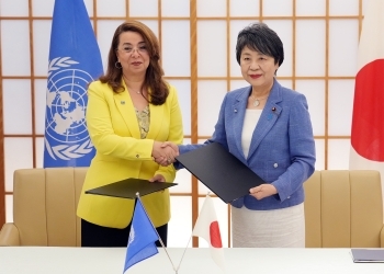 ワーリー事務局長と書簡の交換をし、握手する上川外務大臣