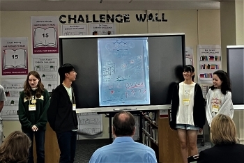 学生4人が黒板を前にプレゼンテーションを行っている