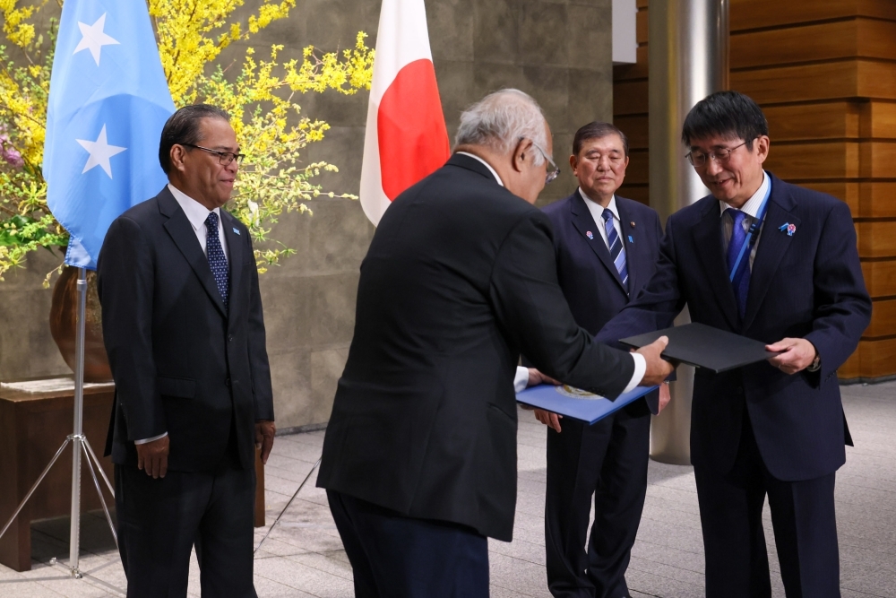 石破総理大臣及びシミナ・ミクロネシア大統領立ち会いの下、無償資金協力の書簡を交換する籠宮駐ミクロネシア日本大使とロバート・ミクロネシア外務大臣