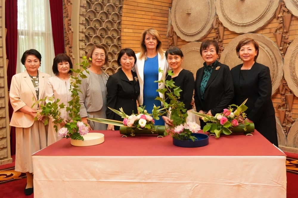 関係者らと共に生け花と記念撮影する両婦人の様子