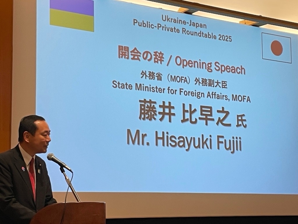 挨拶を行う藤井副大臣。背景にはスクリーンに藤井副大臣と副大臣の名前が映し出されている