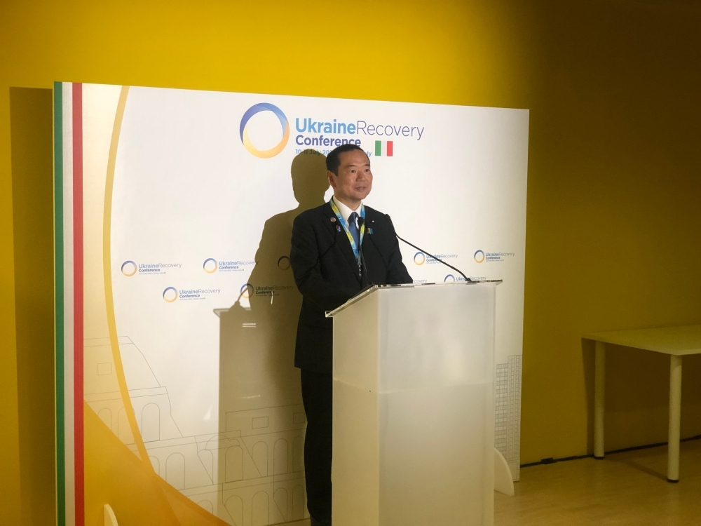 挨拶を行う藤井副大臣。背景にはスクリーンに藤井副大臣が映し出されている