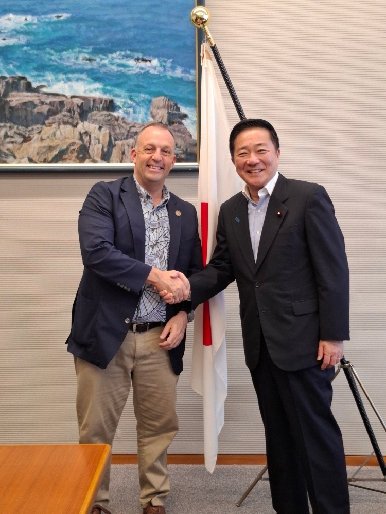 握手する長島総理補佐官とグリーン知事