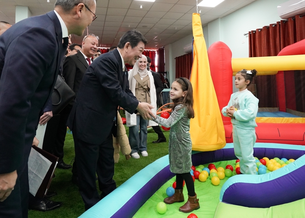 難民の少女を握手をする茂木外務大臣