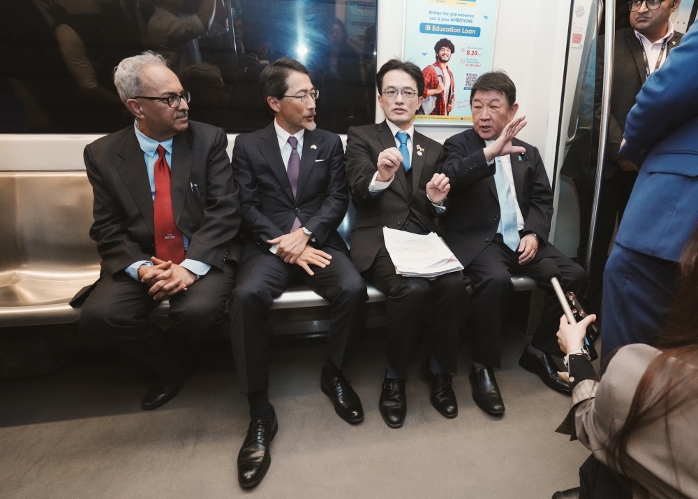 デリーメトロの電車の中で座席に座る茂木外務大臣の様子