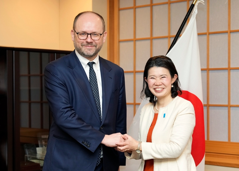 プシダチ・ポーランド大統領府国際政策局長官と国旗の前で握手する国光副大臣