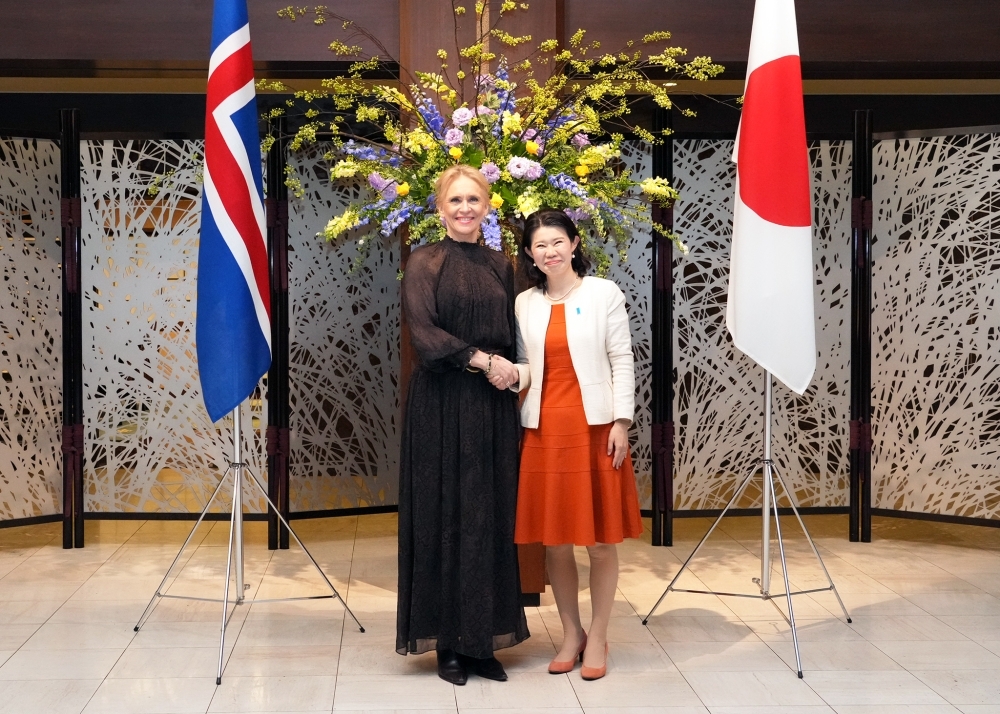 両国国旗の前でグンナルスドッティル・アイスランド外務大臣と笑顔で握手する国光副大臣