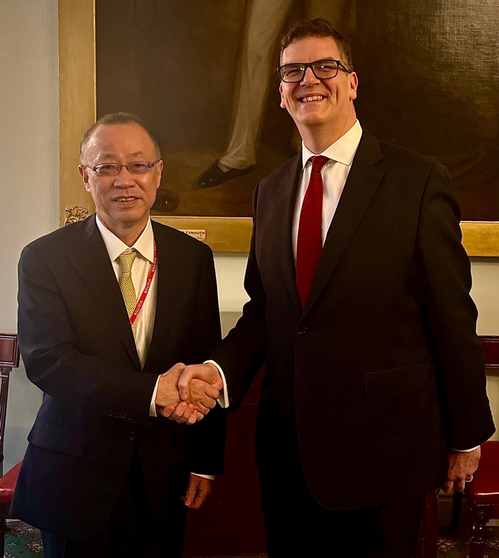 握手をして撮影に応じる船越健裕外務事務次官とオリバー・ロビンス英外務・開発省事務次官