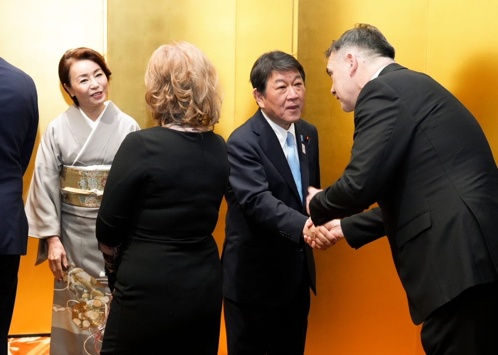 参加者と金屏風の前で握手する茂木外務大臣夫妻