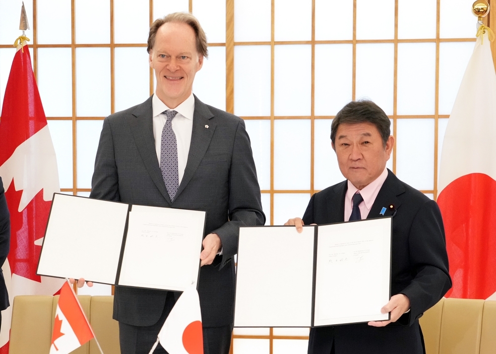 交換した日・カナダ協力覚書を手に撮影に応じる茂木大臣とマッケイ大使