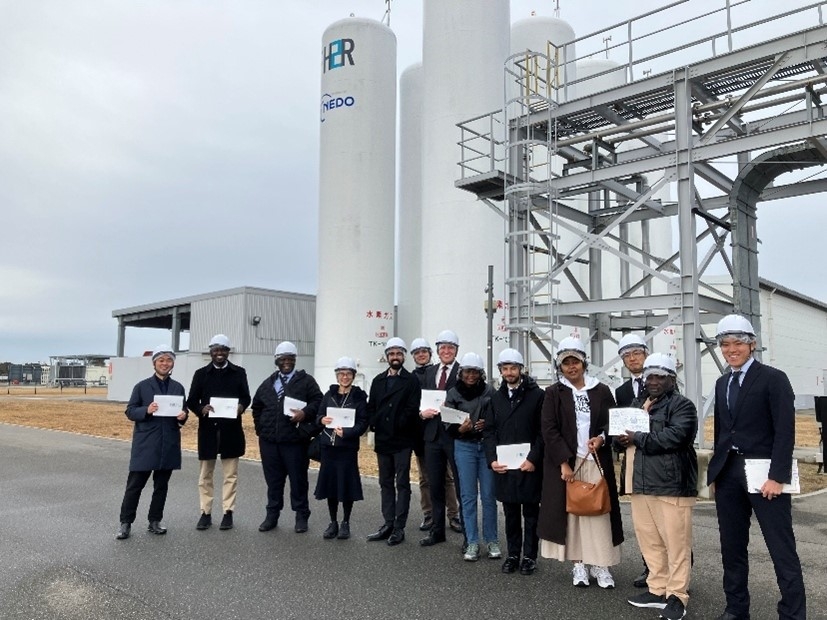 福島水素エネルギー研究フィールドの水素製造設備の前で、記念写真を撮る参加者の様子