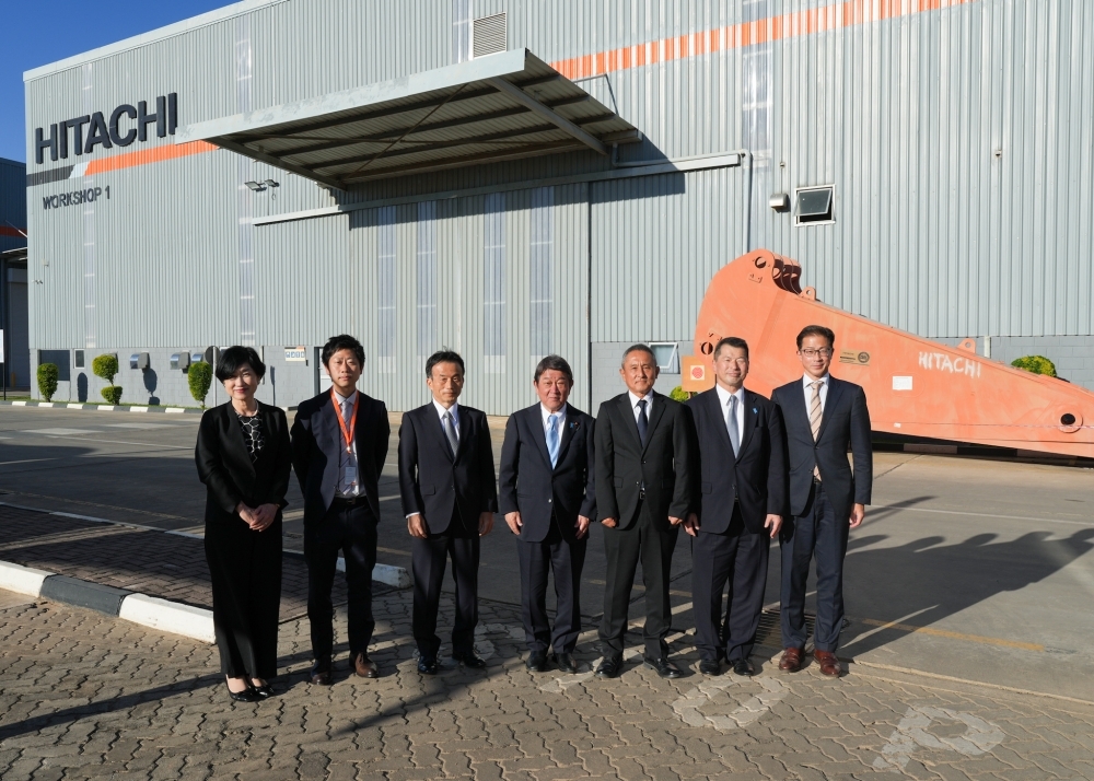 日立建機工場前で関係者と集合写真を撮る茂木外務大臣