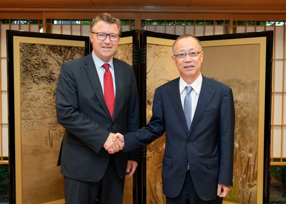 屏風の前で握手する船越次官とフォン・ガイヤー次官