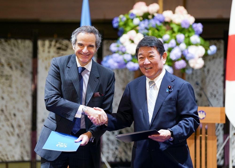 ALPS処理水に関する協力覚書の署名式において、茂木外務大臣とグロッシーIAEA事務局長が署名文書を手に握手する様子