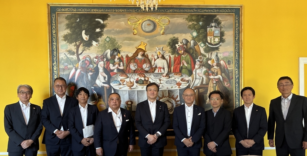 大きな絵画の前で日系企業関係者と写真撮影する堀井副大臣