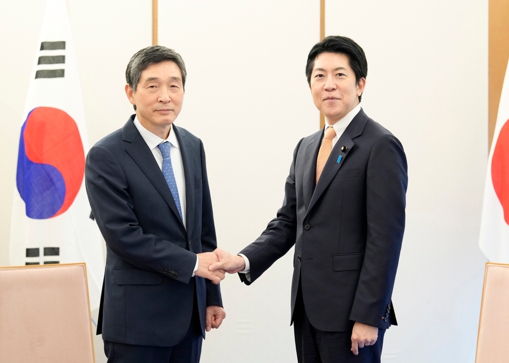 握手をする佐藤官房副長官と李大使