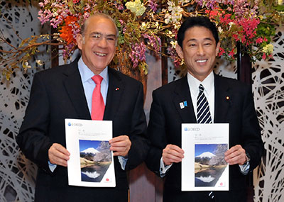 50周年のパンフレットを手に記念撮影に臨むグリアOECD事務総長と岸田外務大臣(右)(4月22日、東京)