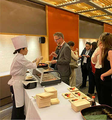 レセプションで実演しながら料理を提供する様子(筆者左)