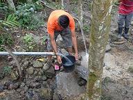 (写真）活動2：対象集落に水供給システムを建設する - 水源における水量の計測の様子