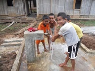 （写真）活動2：対象集落に水供給システムを建設する - バリボ準県レオリマ村において完成した蛇口台で手を洗う事業地の子どもたち