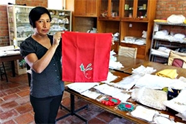 (写真3)本校で学んだ刺繍技術を近隣の女性に教えるクレメンティーナさん。仲間と制作した作品をバザーで販売しています。