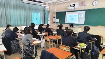 (写真)国際協力局政策課の黒須太記子課長補佐が映し出されたモニターを見る小石川中等教育学校の生徒さんの様子