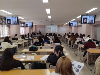 教室内で資料を片手に話を聞く学生たち。