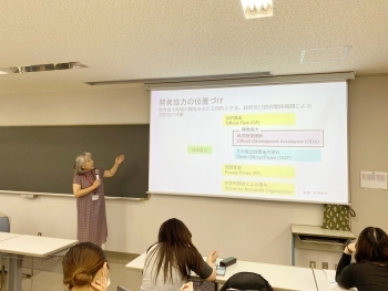 講師がスクリーン左手から投影資料を説明する様子。