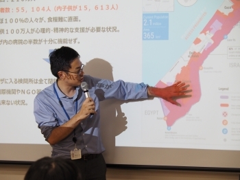 講師が資料を用いて黒板の前で説明する様子。