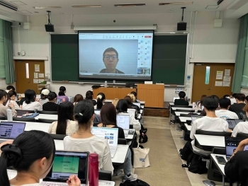 ライブ配信によるODA出前講座に参加する神戸大学の学生たち。正面のスクリーンには、門脇講師が説明を行っている様子が映し出されている。