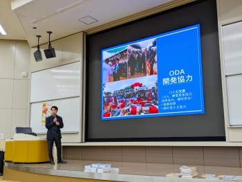 講師が前方に立ち、アフリカ地域の写真を投影しながら、日本の開発協力について説明している場面。