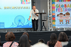 （写真7）ブータン流の挨拶を披露する写真家・関健作さん。