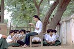 戸外で授業を行う先生と生徒たちの写真