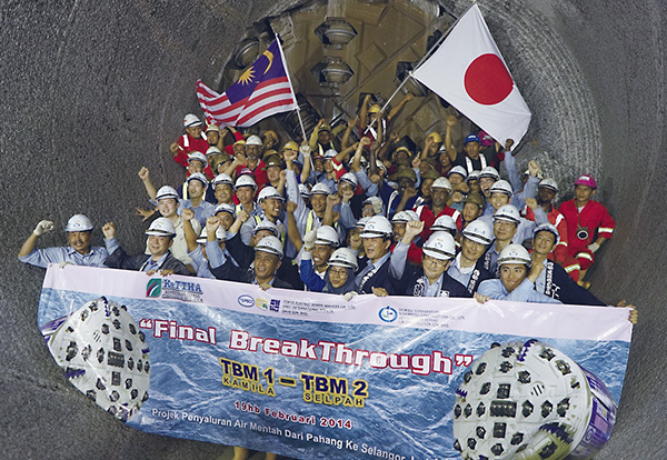 掘削機TBMの前でトンネル貫通を喜ぶ作業員たち(写真:清水建設)