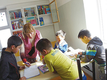 モンゴル・ウブルハンガイ県の学校寄宿舎に設置された図書の貸し出しコーナーで本の管理方法を子どもたちに教える青年海外協力隊の玉井良枝さん(写真:塚越貴子)